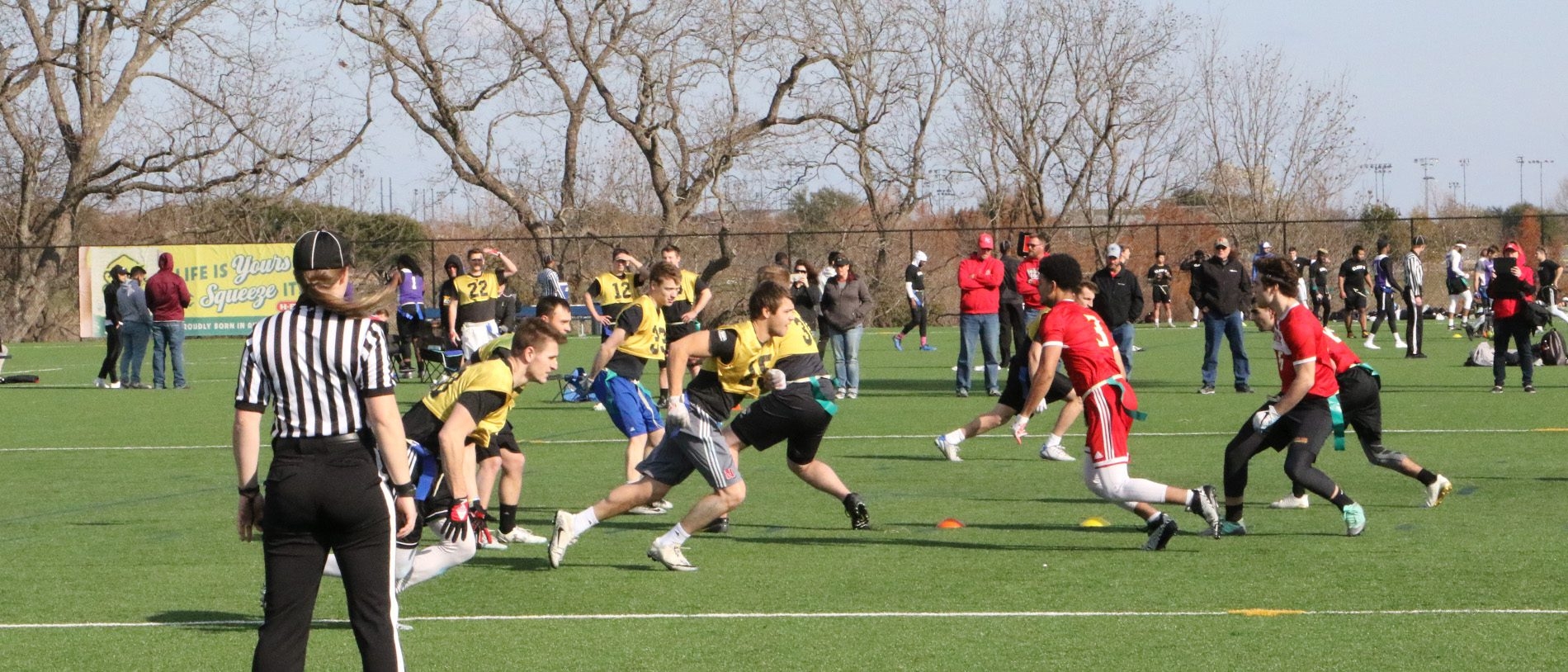 two flag football teams running towards each other with referee watching the play