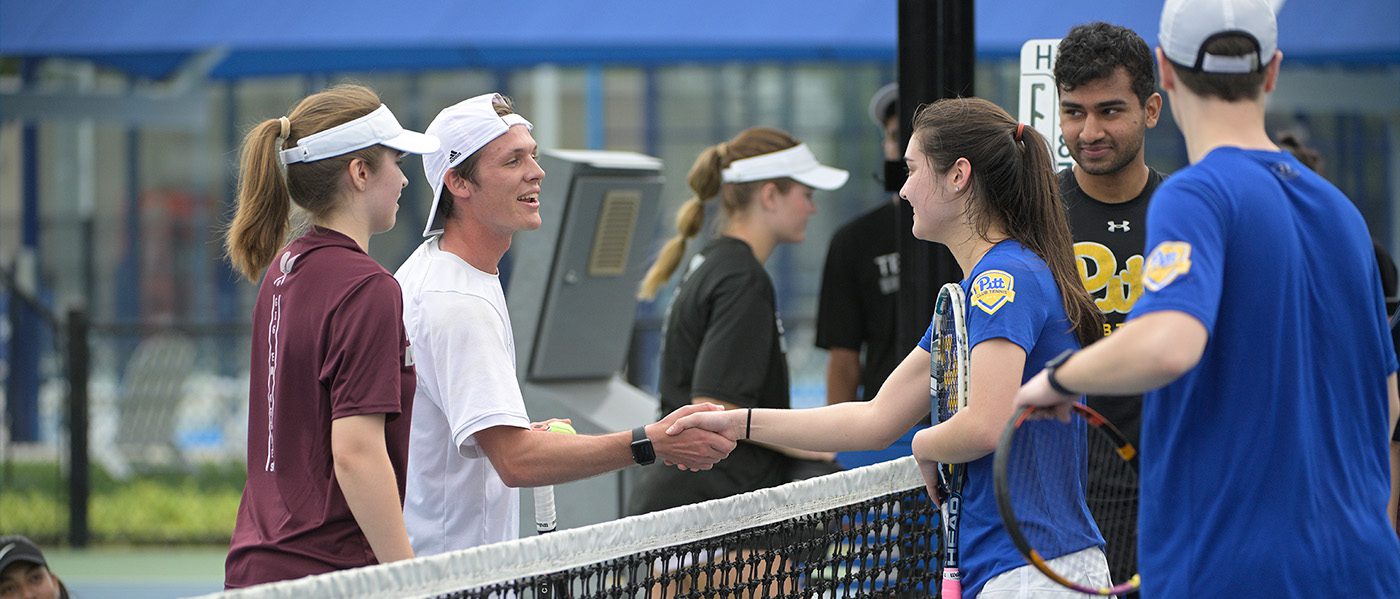 two double tennis teams shaking hands over net
