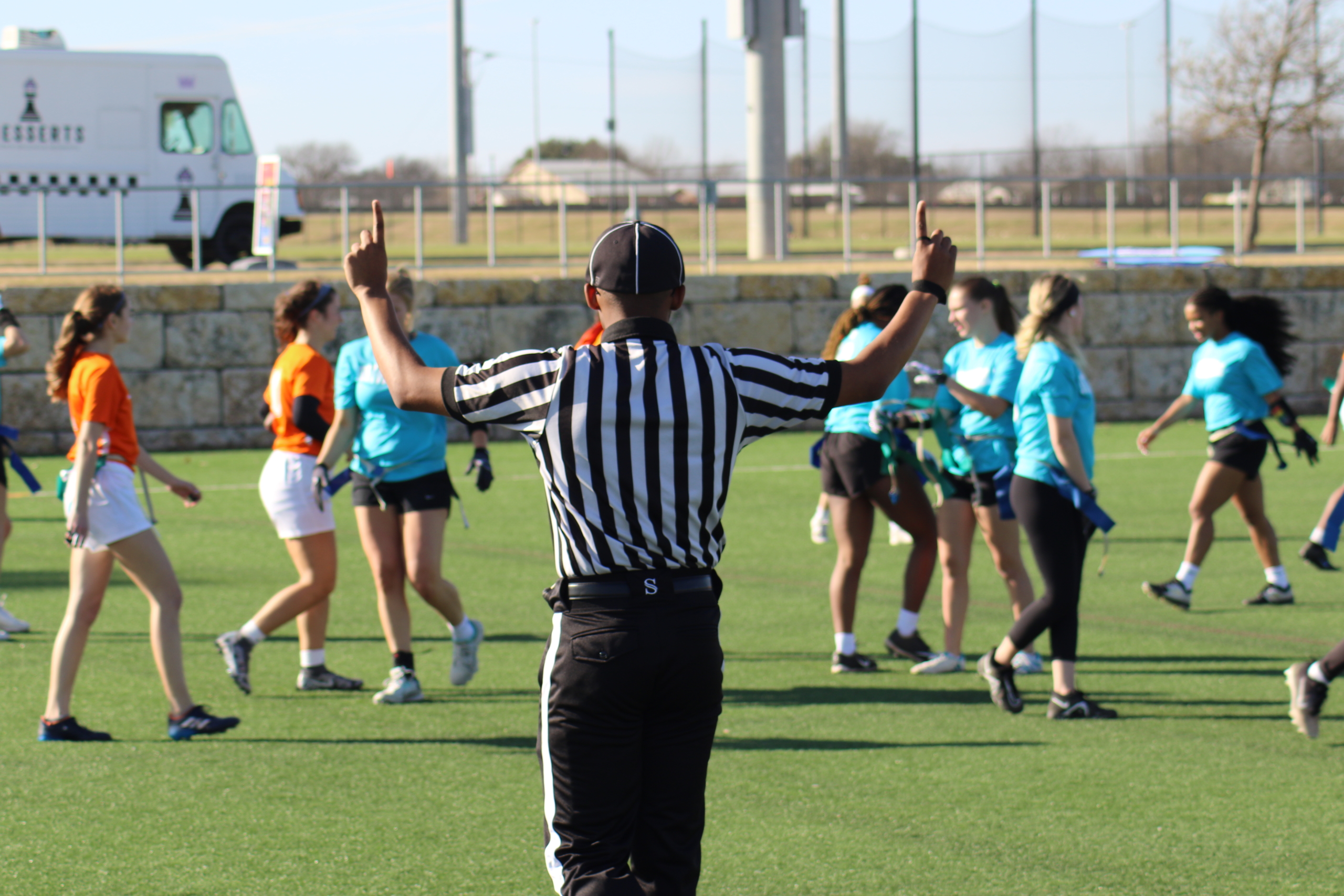 Back of flag football official on outside field calling a play